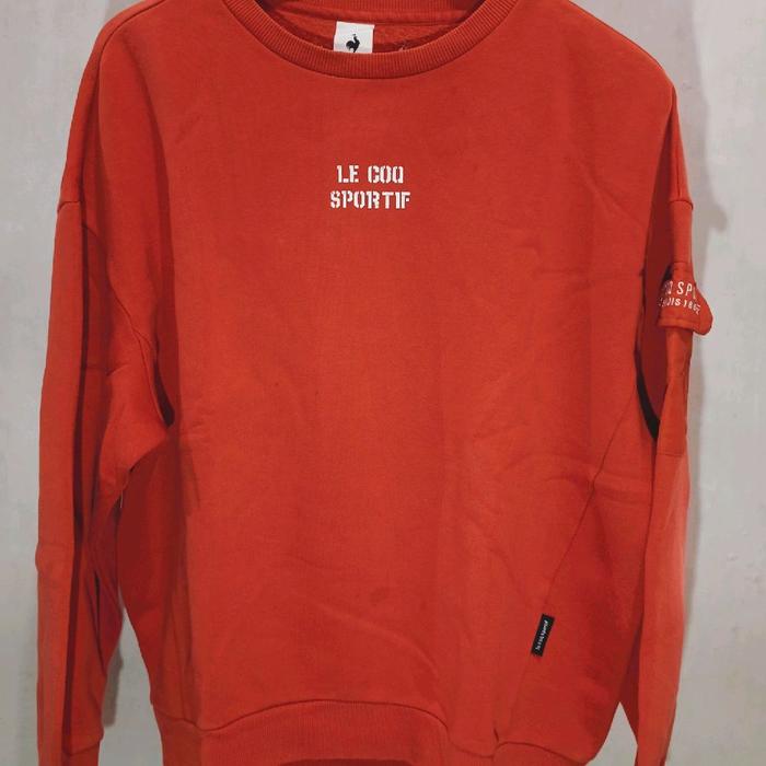 Le Coq Sportif Sweater Merah Bata dengan Logo Putih dan Detail Saku di Lengan