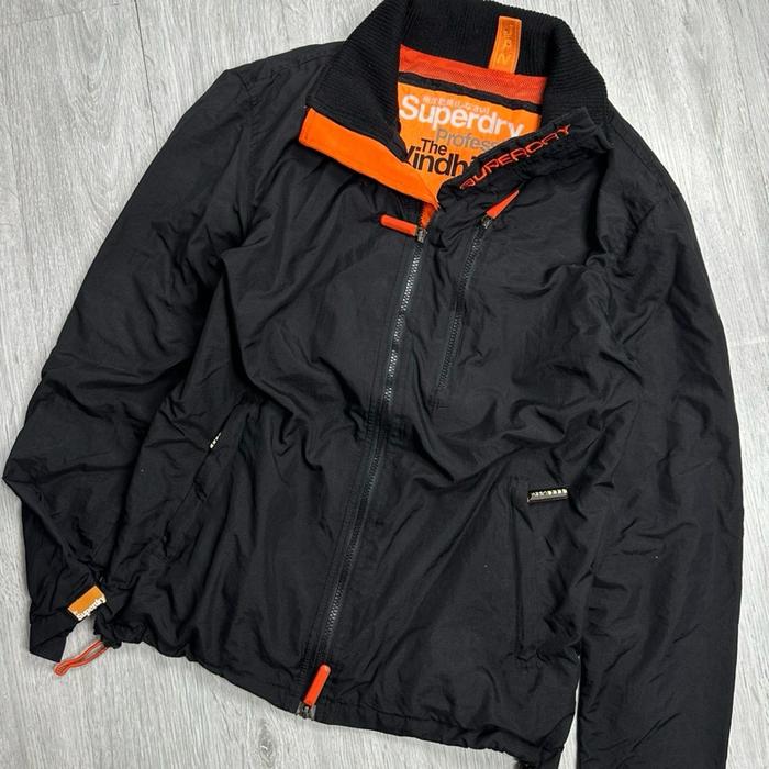 Superdry Jaket Outdoor Superdry Japan Hitam dengan Detail Oranye untuk Aktivitas Luar Ruangan