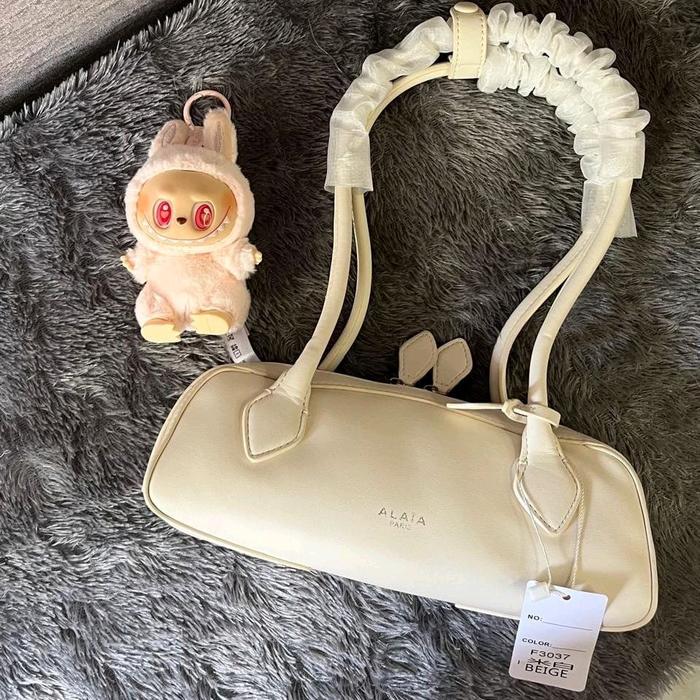 Alaia Tas Wanita Alaia Model F3037 Warna Beige dengan Aksesori Boneka Lucu