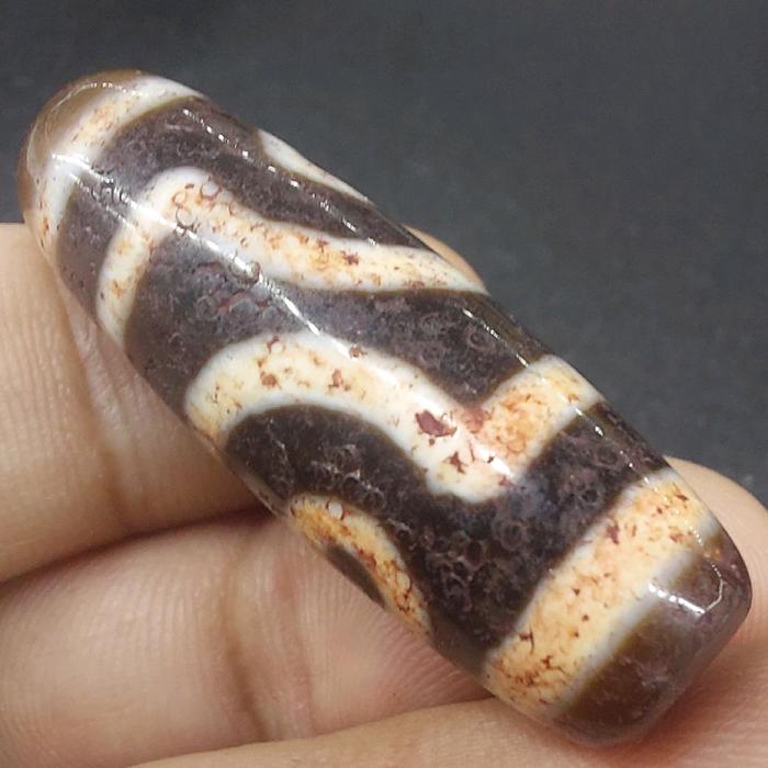 A 2-eye Dzi bead with bloodspots is a rare natural agate bead featuring distinct red or brownish iro